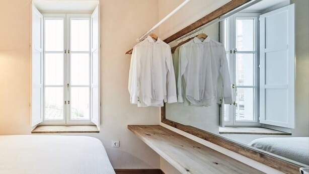 Ein Schlafzimmer mit großem Fenster, einer Holzbank und einem Spiegel.