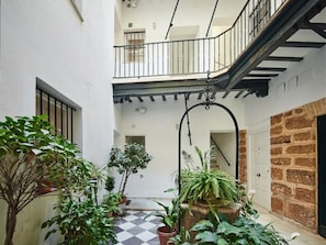 A narrow courtyard with potted plants, a checkered floor, a staircase, and a brick wall. - Apartamento Mes n C diz by Livework (Cádiz)