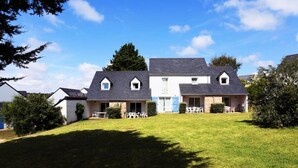 A two-story house with a sloped roof, a front porch with outdoor seating, and a well-maintained lawn. - 2 Rooms 4 People (Locmaria-Plouzane)