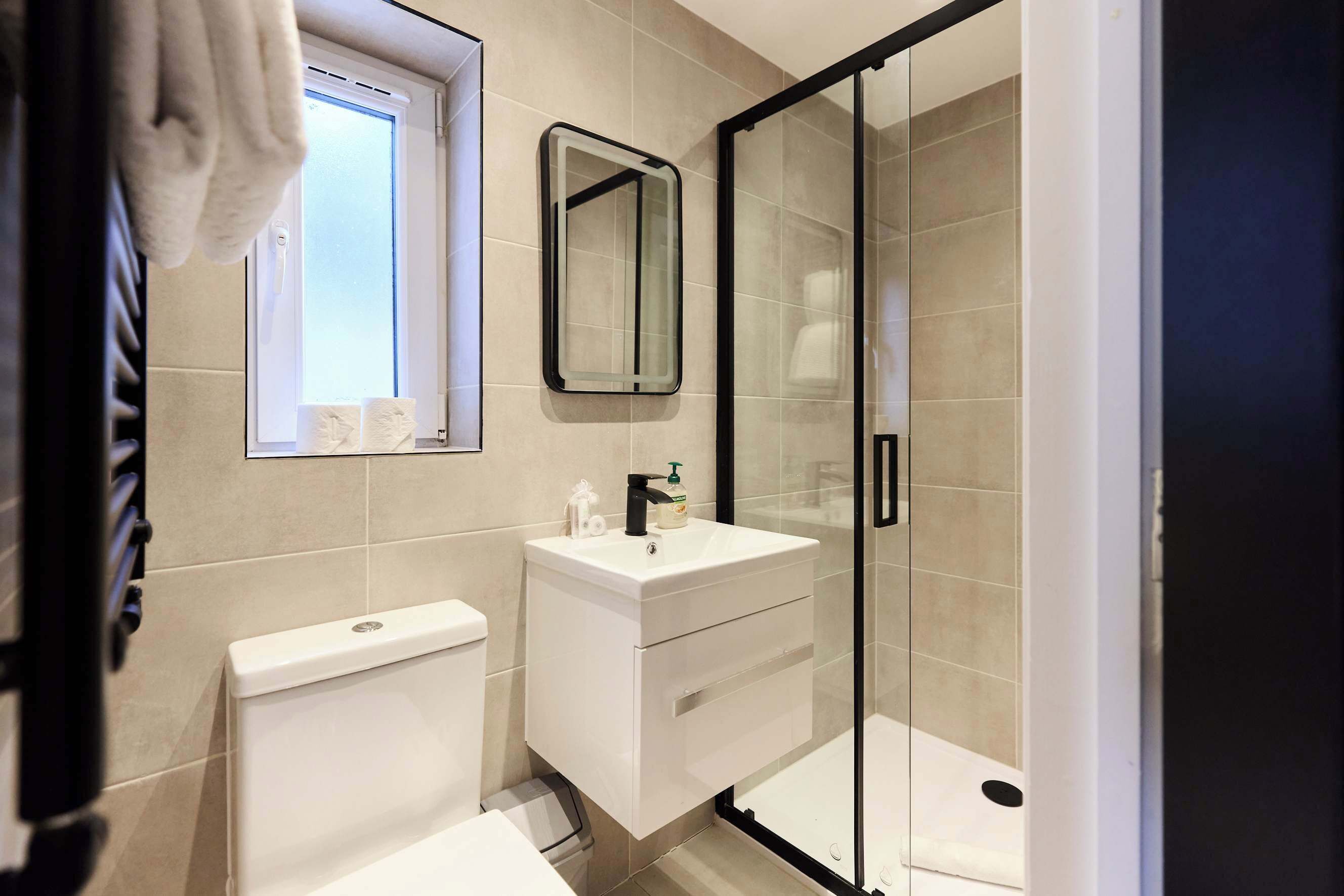 A bathroom with a toilet, a sink with a mirror, and a shower area.
