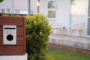 A mailbox with the number 130, a wooden bench, and a small patio area with a table and chairs. - Bay Breeze at Salamander Bay (Salamander Bay)