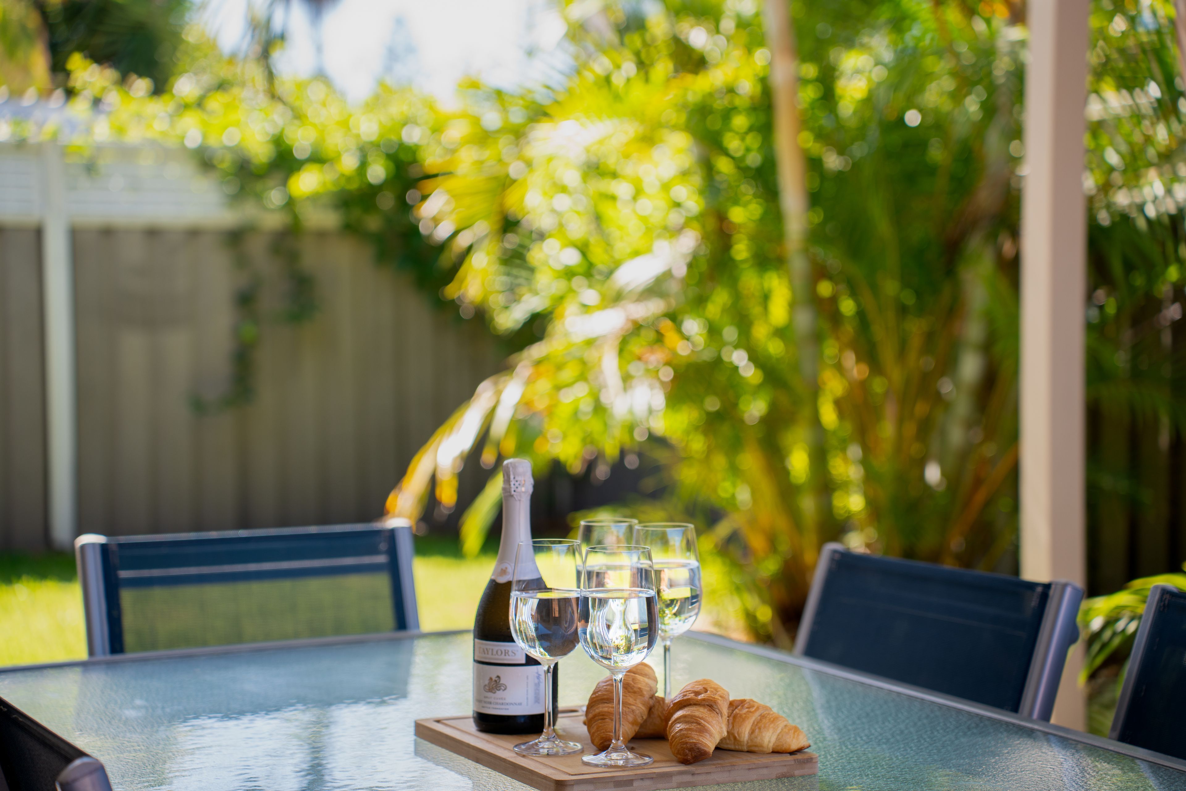 A table with a bottle of wine, two glasses, and croissants.