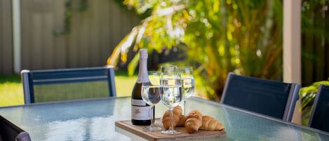 A table with a bottle of wine, two glasses, and croissants.
