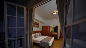 A bedroom with a bed, wooden headboard, bedside table, and a mirror. - BPR Asgiriya (Kandy)