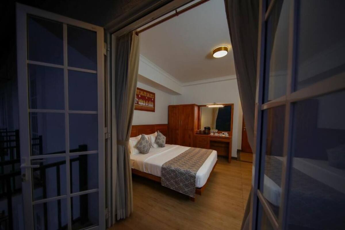 Ein Schlafzimmer mit einem Bett, einem hölzernen Kopfteil, einem Nachttisch und einem Spiegel.