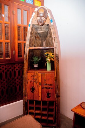 Un meuble en bois orné d’une façade sculptée, une plante en pot et un vase rempli de fleurs.