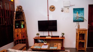 A living room with a wooden coffee table, a television, a bookshelf, and a door.