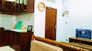 A kitchen with wooden cabinets, a sink, and a television. - Kay's Place Train House Colonel tours (Zanzibar)