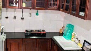A kitchen with wooden cabinets, a gas stove, and a sink. - Kay's Place Train House Colonel tours (Zanzibar)
