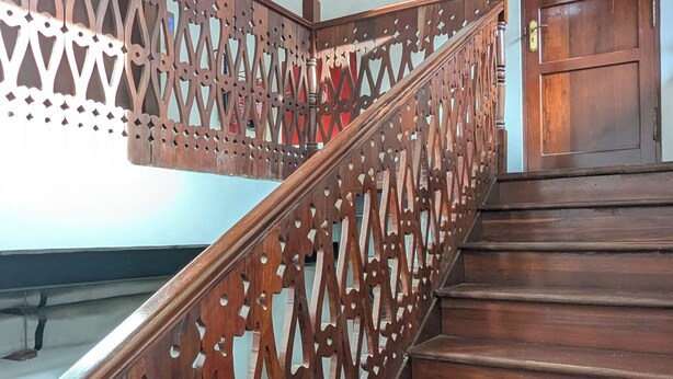 A wooden staircase with intricate railings leading to a door labeled 'BAMBOO'. - Kay's Place Train House Colonel tours (Zanzibar)