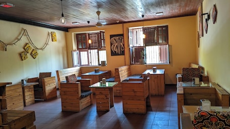 A cozy restaurant with wooden furniture, large windows, and a tiled floor.