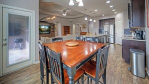 Una cocina amplia con electrodomésticos modernos, un comedor con mesa y sillas de madera, y una sala de estar con televisor.