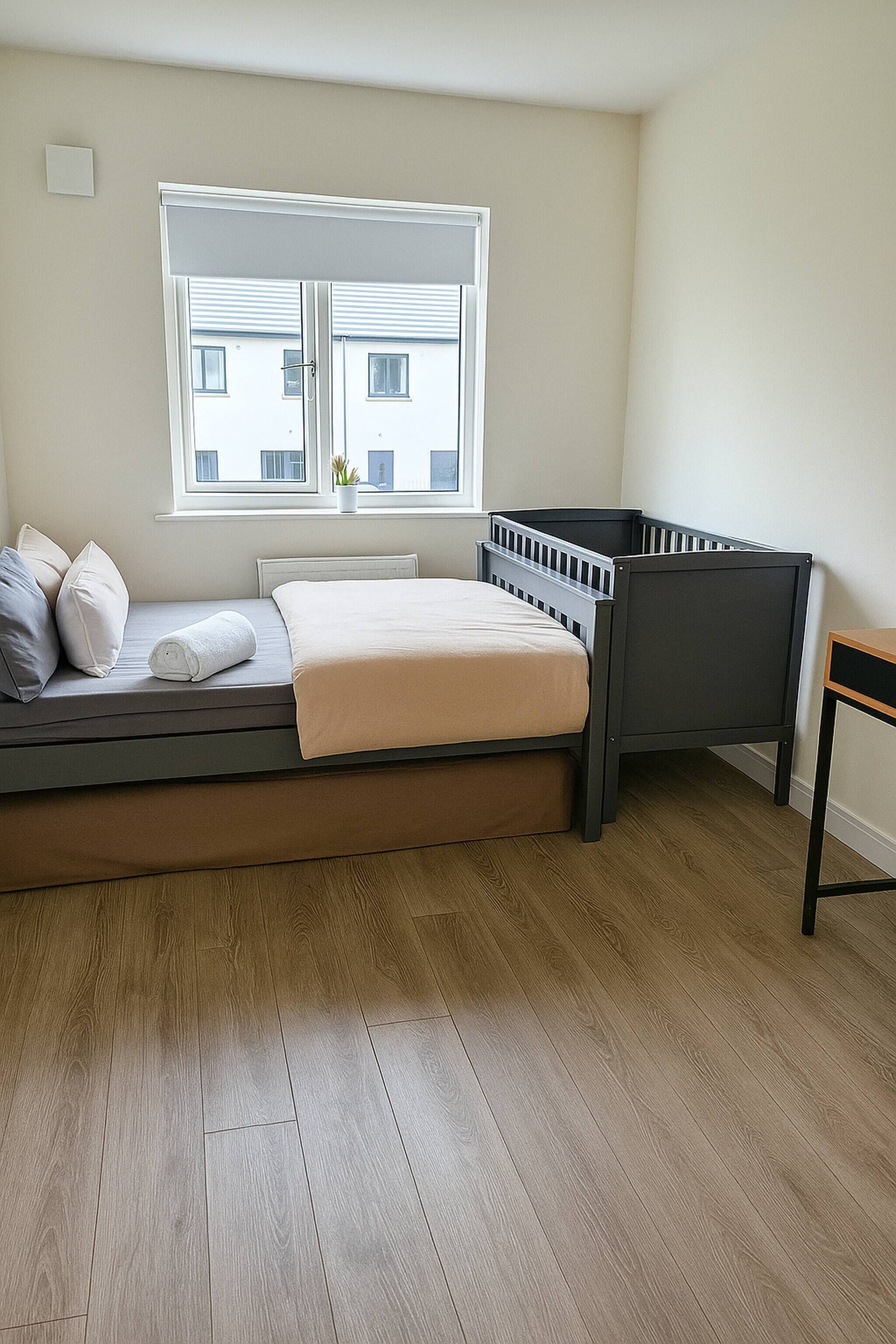 Ein Zimmer mit einem Bett, einem Fenster und Blick auf Gebäude.