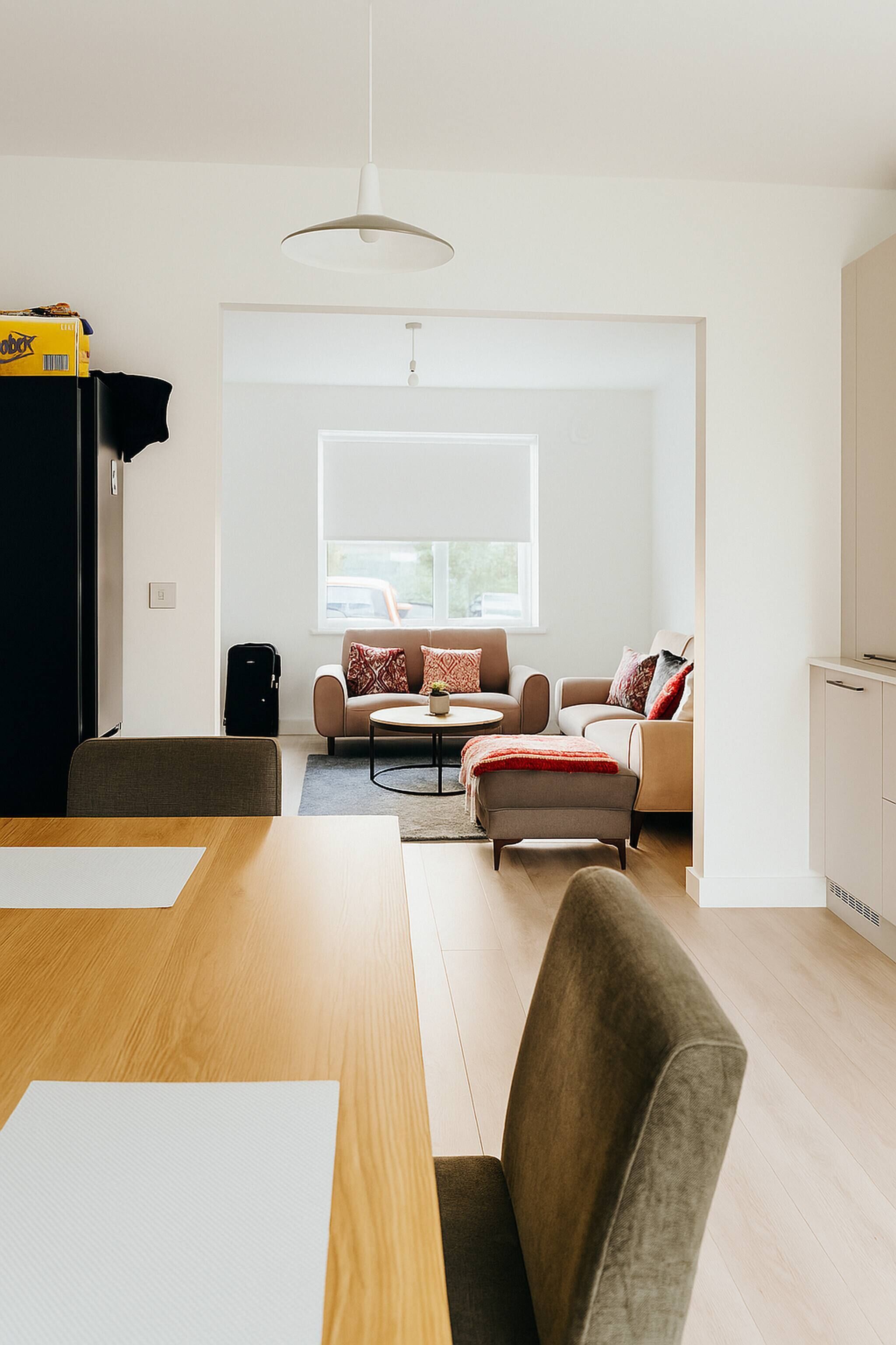 Ein modernes Wohnzimmer mit einer Sofagarnitur, einem Esstisch und einem großen Fenster.