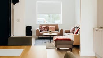 Ein modernes Wohnzimmer mit einer Sofagarnitur, einem Esstisch und einem großen Fenster.