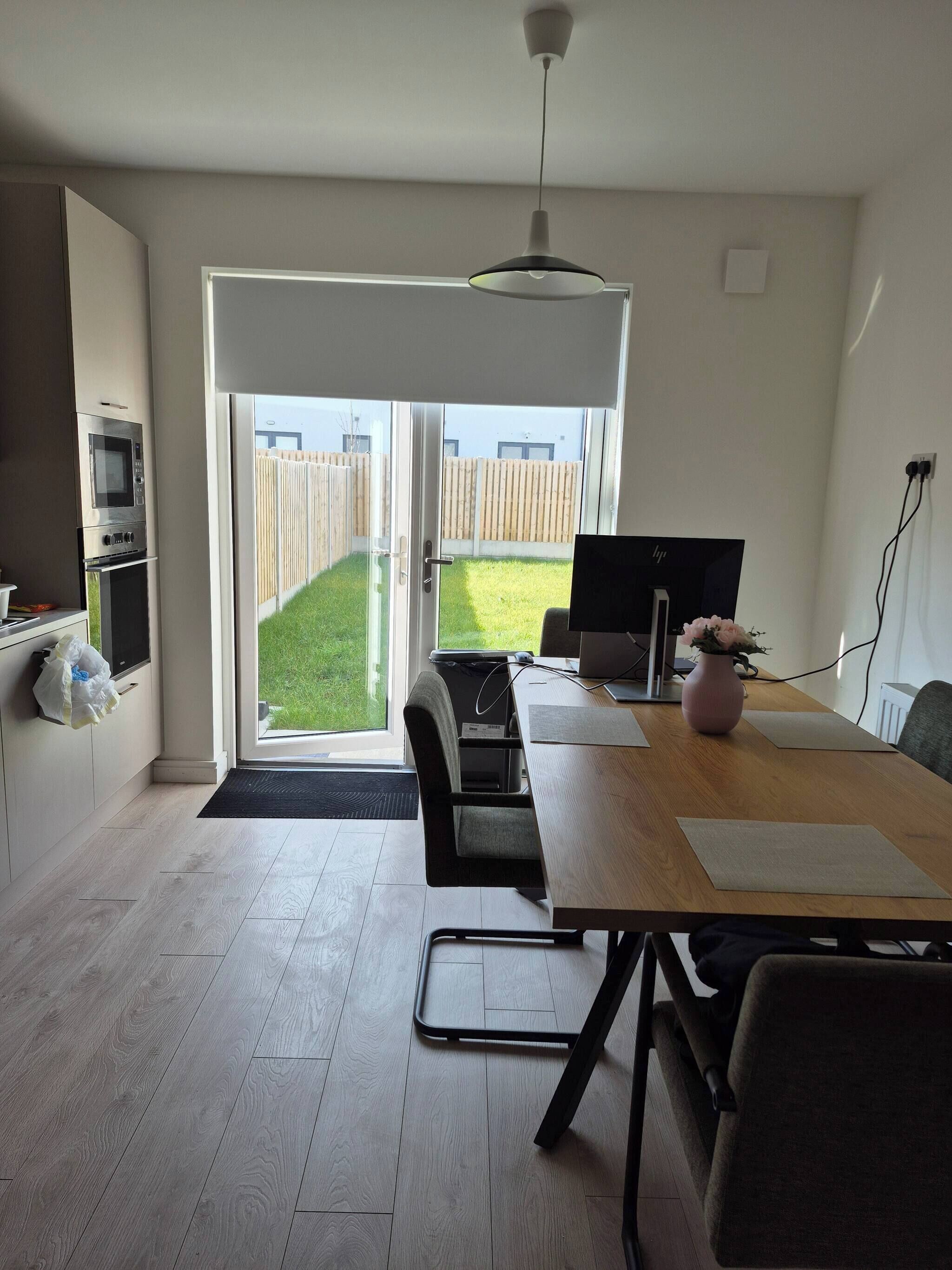 Eine moderne Küche mit eingebauten Geräten, ein Essbereich mit Tisch und Stühlen sowie eine große Schiebeglasdoor zur hinteren Terrasse.
