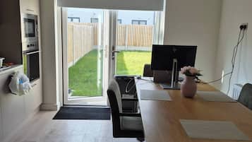 Eine moderne Küche mit eingebauten Geräten, ein Essbereich mit Tisch und Stühlen sowie eine große Schiebeglasdoor zur hinteren Terrasse.
