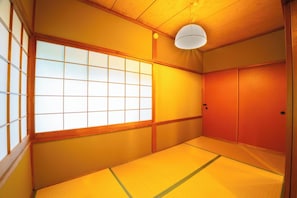 Una habitación japonesa tradicional con suelo de tatami, puertas correderas y un biombó shoji.