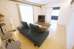 A living room with a sofa, a coffee table, a TV, and a dining area.