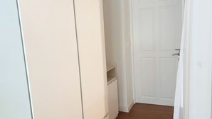 En hall med en vit dörr, en vit vägg och ett brunt golv.