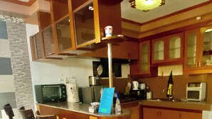 A kitchen with a central island, bar stools, a microwave, and a coffee maker. - LENS STAYCATION PANABO 3BDR 2BR KTCHN (Panabo)
