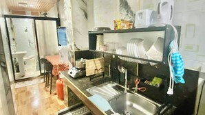 Una cucina compatta con lavello, piano di lavoro e zona pranzo con tavolo e sedie.