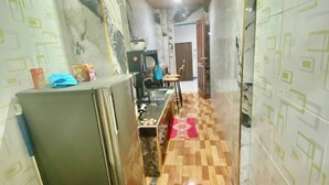Un corridoio stretto con angolo cottura, frigorifero, lavello e pavimento in legno.