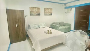 Una camera da letto con un letto, una ventola, un armadio e due condizionatori d'aria a muro.