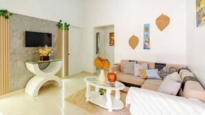 Una sala de estar moderna con un sofá, una mesa de centro, un televisor y elementos decorativos.