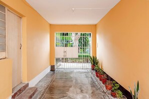 A corridor with a tiled floor, a metal gate, and potted plants along one wall. - Cozy 2BR - Heart of Barranco - Walk to Everywhere (Barranco)