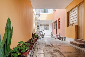 A narrow courtyard with potted plants, a bicycle, and a staircase leading to an upper level. - Cozy 2BR - Heart of Barranco - Walk to Everywhere (Barranco)