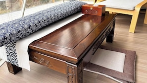 Una panca di legno con un cuscino decorato, una piccola scatola di legno e un tappeto tessuto.