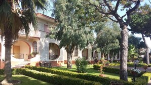 Un cortile con un edificio caratterizzato da finestre ad arco e un prato curato.
