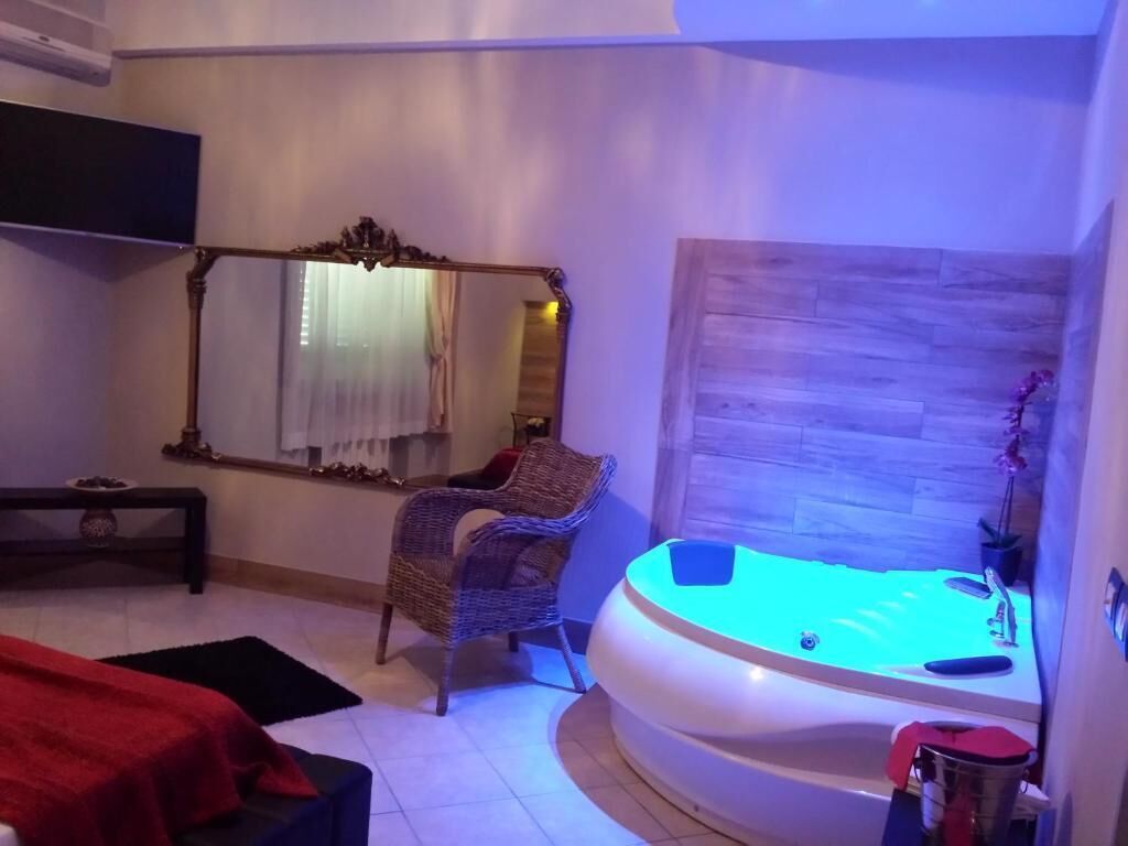 Una stanza spa con uno specchio grande, una poltrona massaggiante, un lettino da massaggio e una vasca idromassaggio.