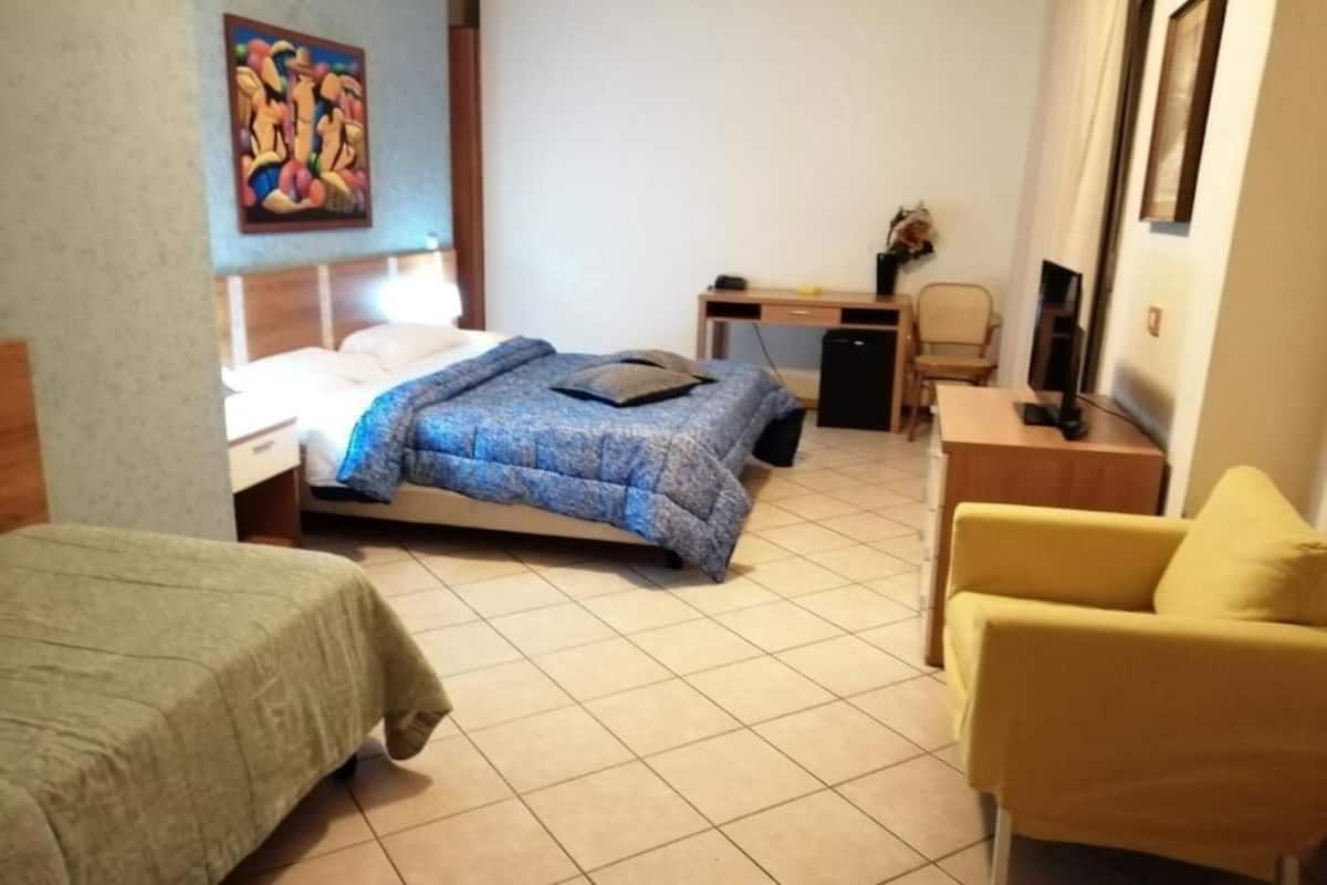 A hotel room with a bed, a desk, a chair, and a television.