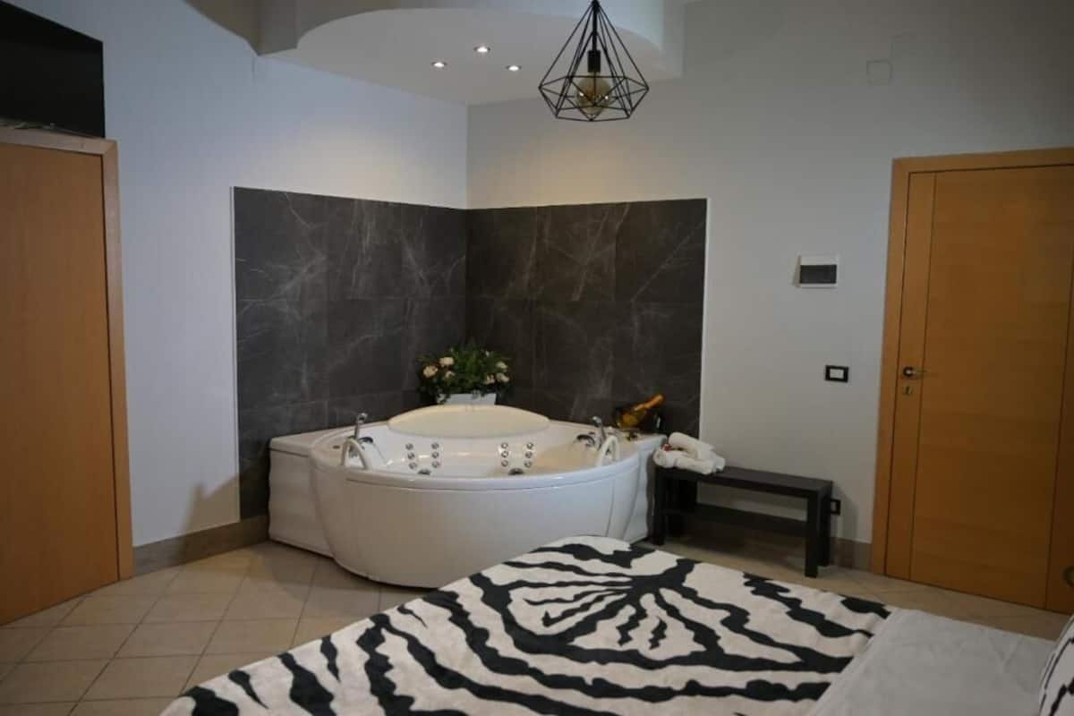 A modern bathroom with a freestanding bathtub, a bench, and a zebra-patterned rug.