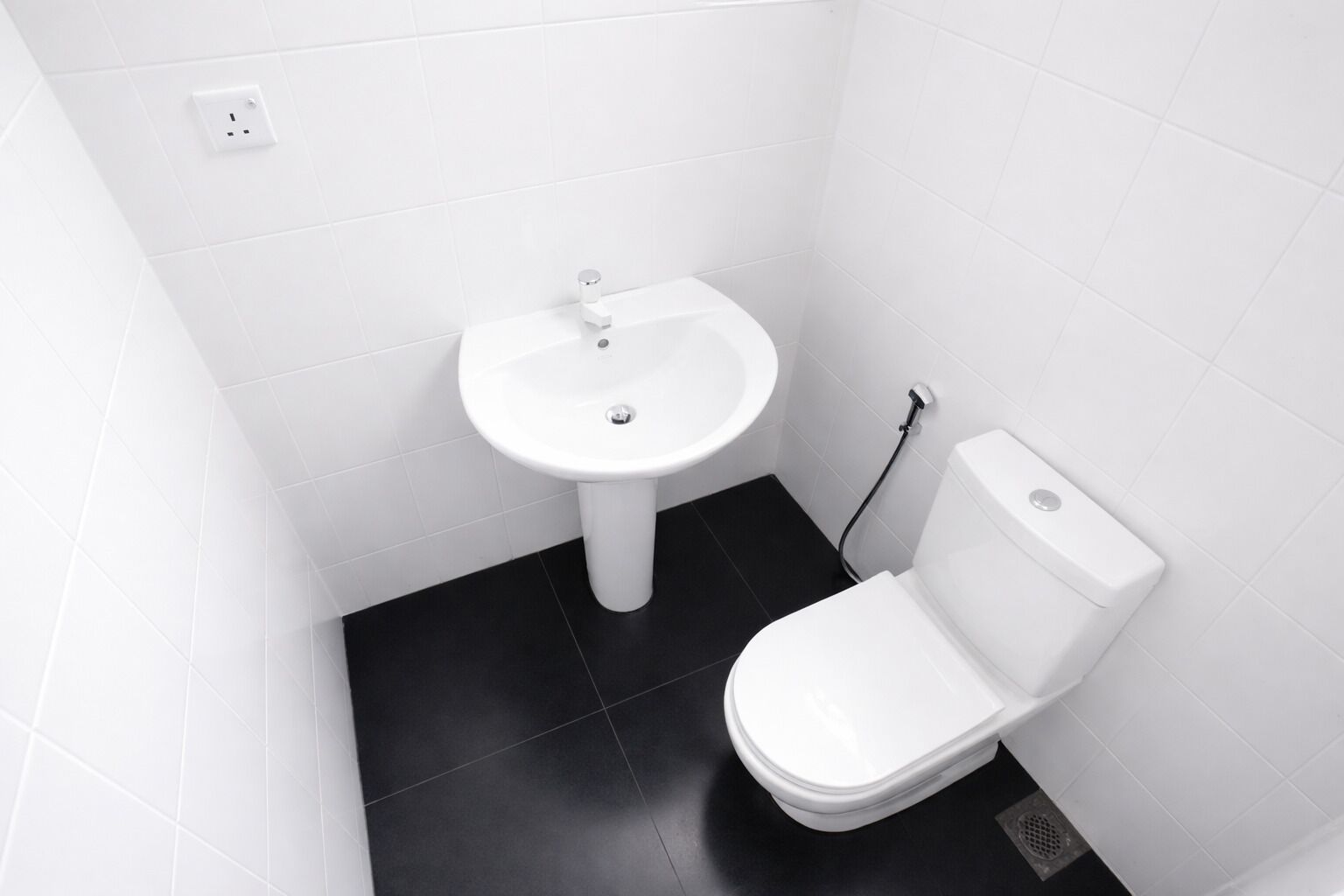 A small, white-walled bathroom with a white sink and toilet.