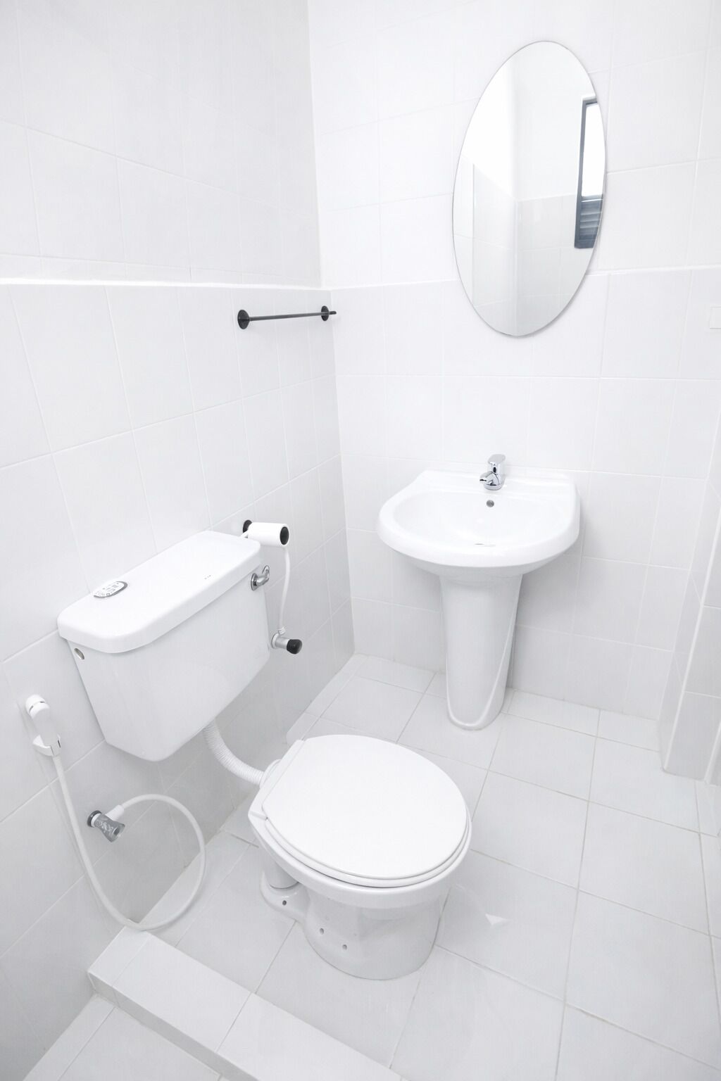 A modern bathroom with a toilet, bidet, sink, and mirror.