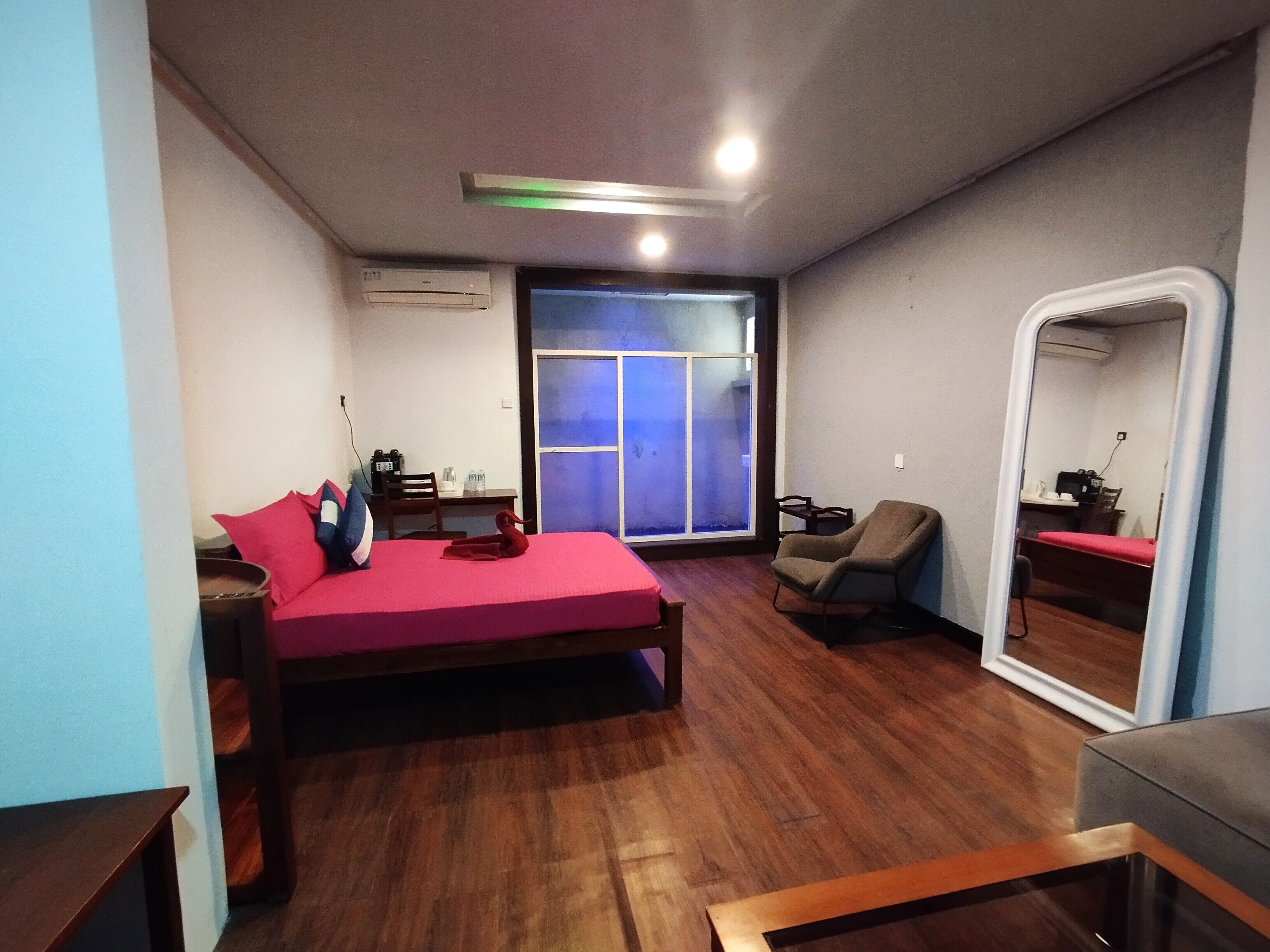 A bedroom with a bed, a chair, a desk, a window, and an air conditioning unit.