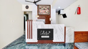 A reception desk with a marble top, a ceiling fan, a fire extinguisher, and a framed picture on the wall. - Super Hotel O MVP Double Road (Visakhapatnam)