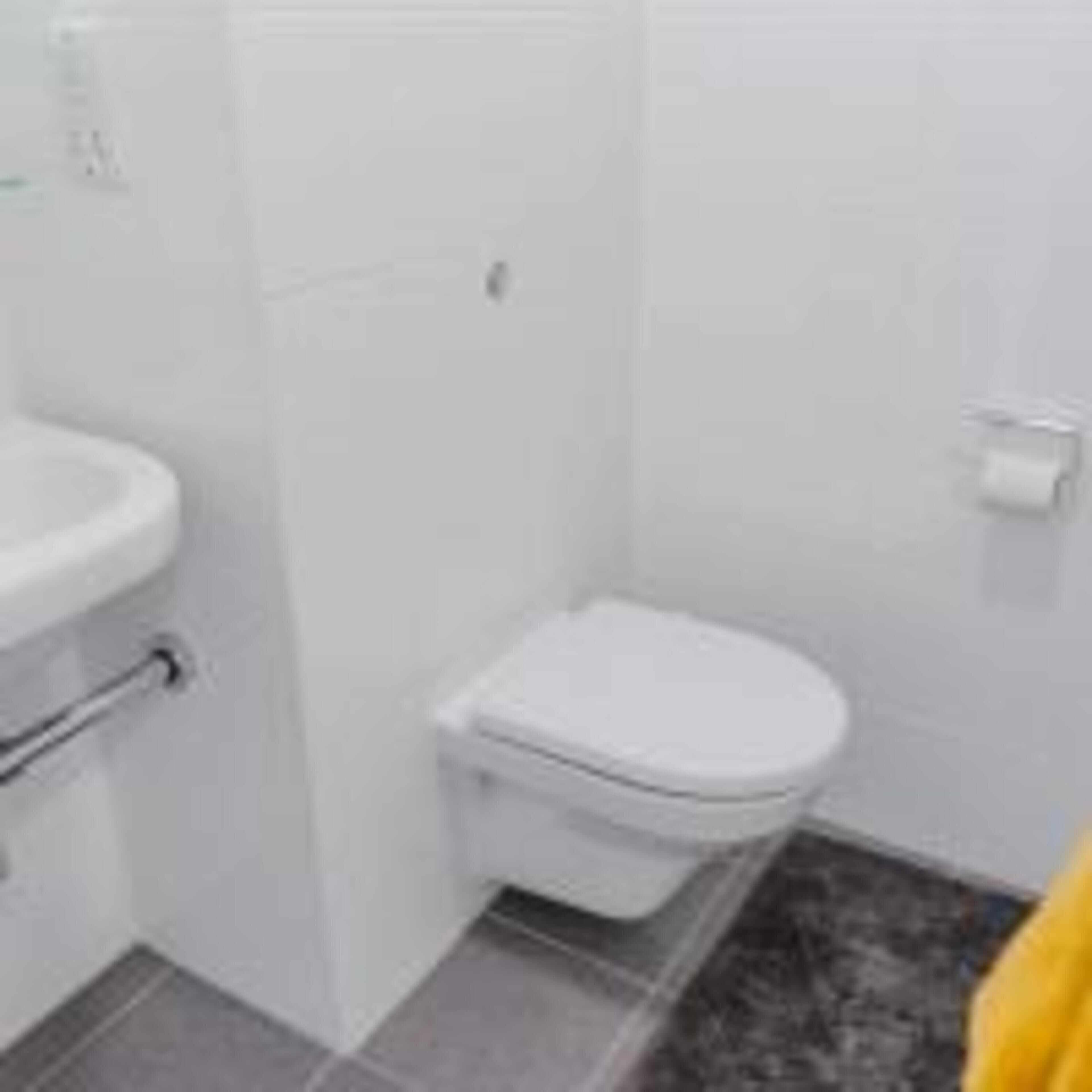 A small bathroom with a toilet, a sink, and a shower area.