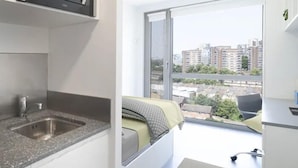 A modern kitchen with a built-in microwave and a large window overlooking a cityscape. - Student Only Studio Chapter Lewisham (London)