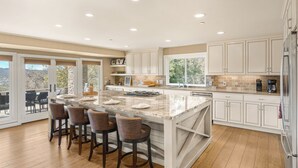 A spacious kitchen with a large island, white cabinetry, and a view through the glass doors. - Sleeps 18, 2 Homes | Vineyard Estate + Pool + Hot Tub | Minutes to Templeton (Templeton)