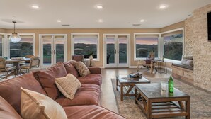 A spacious living area with a leather sofa, a wooden coffee table, and a view through large glass doors. - Sleeps 18, 2 Homes | Vineyard Estate + Pool + Hot Tub | Minutes to Templeton (Templeton)