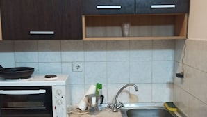 Pieni, käytännöllinen keittiö, jossa on mikroaaltouuni, pesuallas ja kaapistot.
