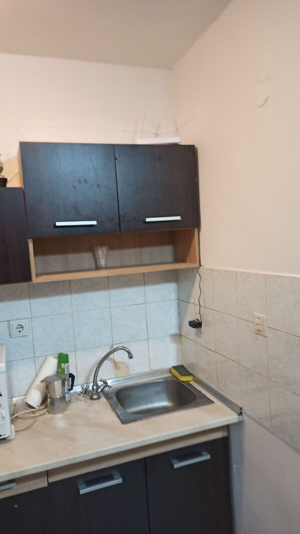 Una cucina con lavello, pensili e piano di lavoro.