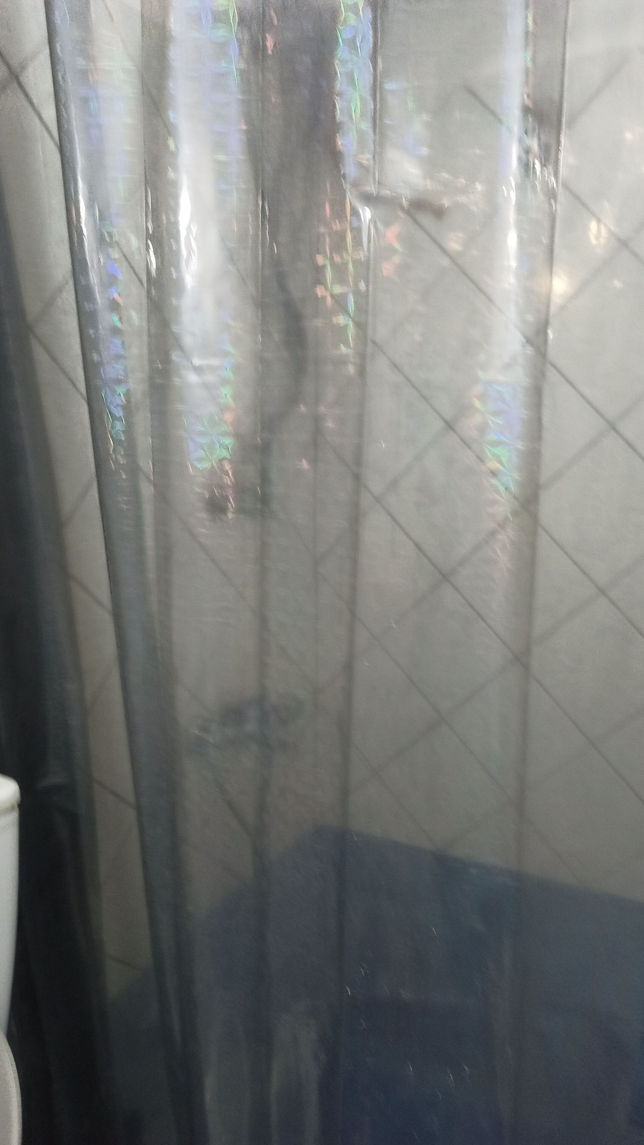A bathroom with a shower curtain and tiled walls.