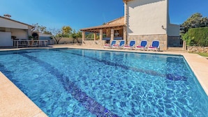A swimming pool with clear blue water, a covered seating area with chairs, and a building with a tiled roof. - Holiday Home "Yesero" with Mountain View, Pool, Wi-Fi & Garden (Illes Balears)