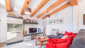 A modern living room with a sofa, a coffee table, a TV, and a bookshelf. - Holiday Home "Yesero" with Mountain View, Pool, Wi-Fi & Garden (Illes Balears)