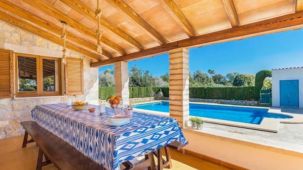 A covered outdoor dining area with a pool view, stone walls, and wooden beams. - Holiday Home "Yesero" with Mountain View, Pool, Wi-Fi & Garden (Illes Balears)